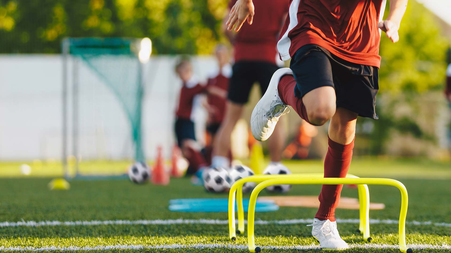 Kinder spielen Fußball, Jugendmannschaft, Trainierende laufen über kleine Hürden