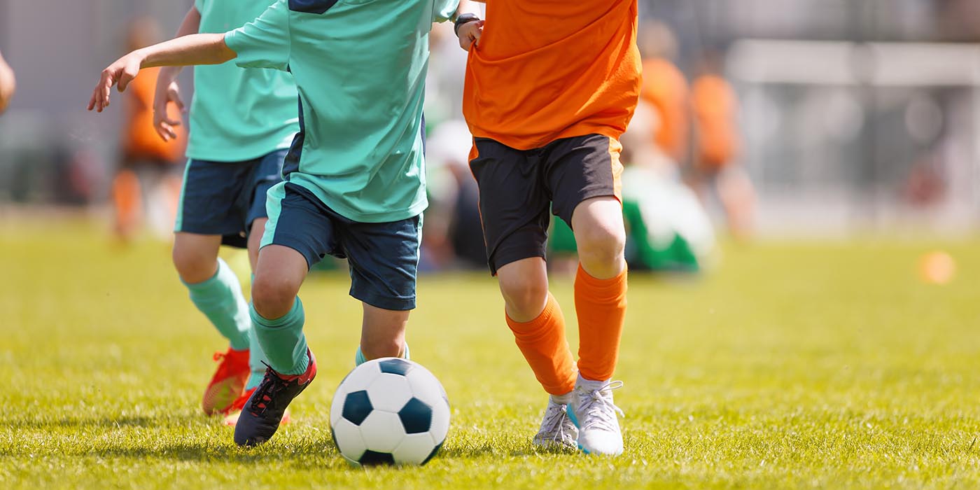Kinder spielen Fußball, Jugendmannschaft, mehrere SpielerInnen laufen einem Ball hinterher